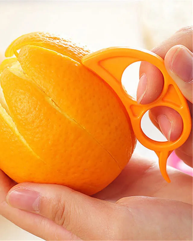 Orange being peeled with a manual peeler held by a hand.