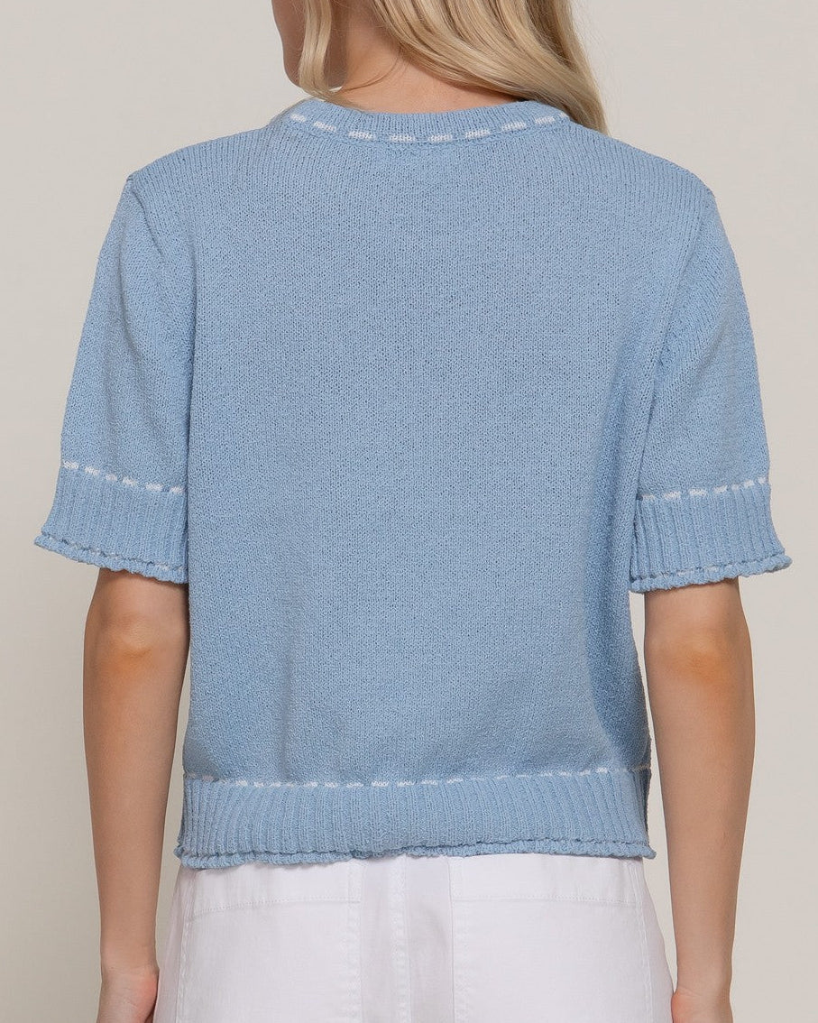 Light blue knitted top worn by a person on a plain background