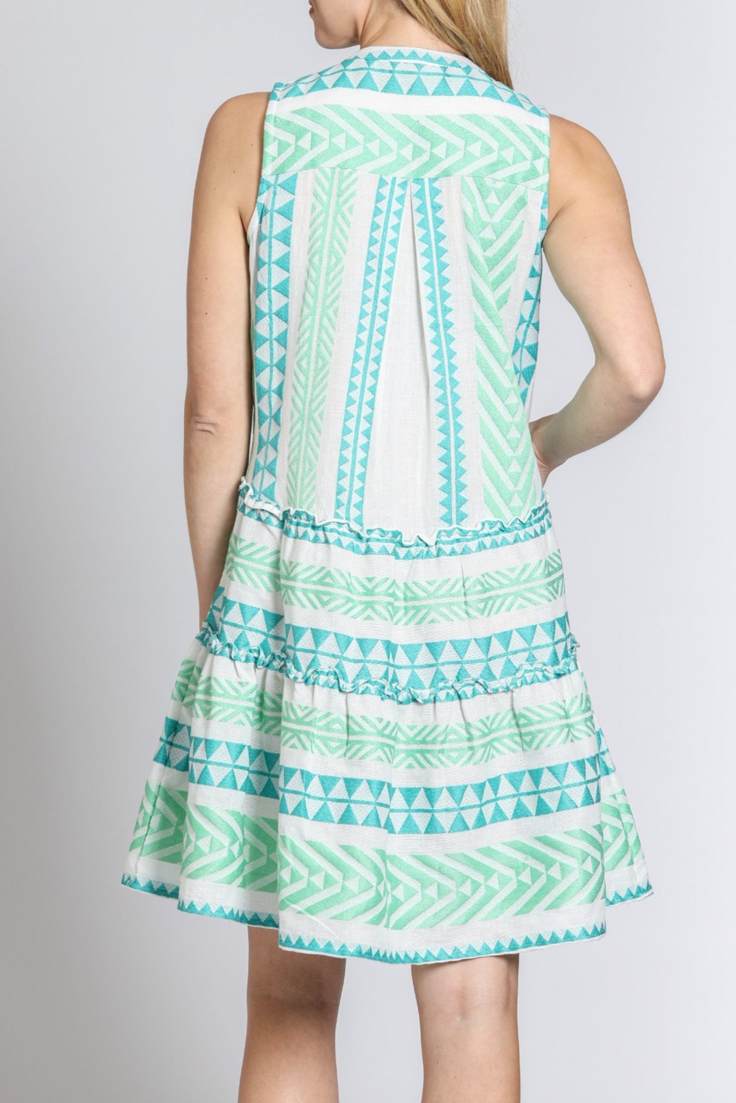 Woman wearing a sleeveless dress with a geometric pattern on a plain background