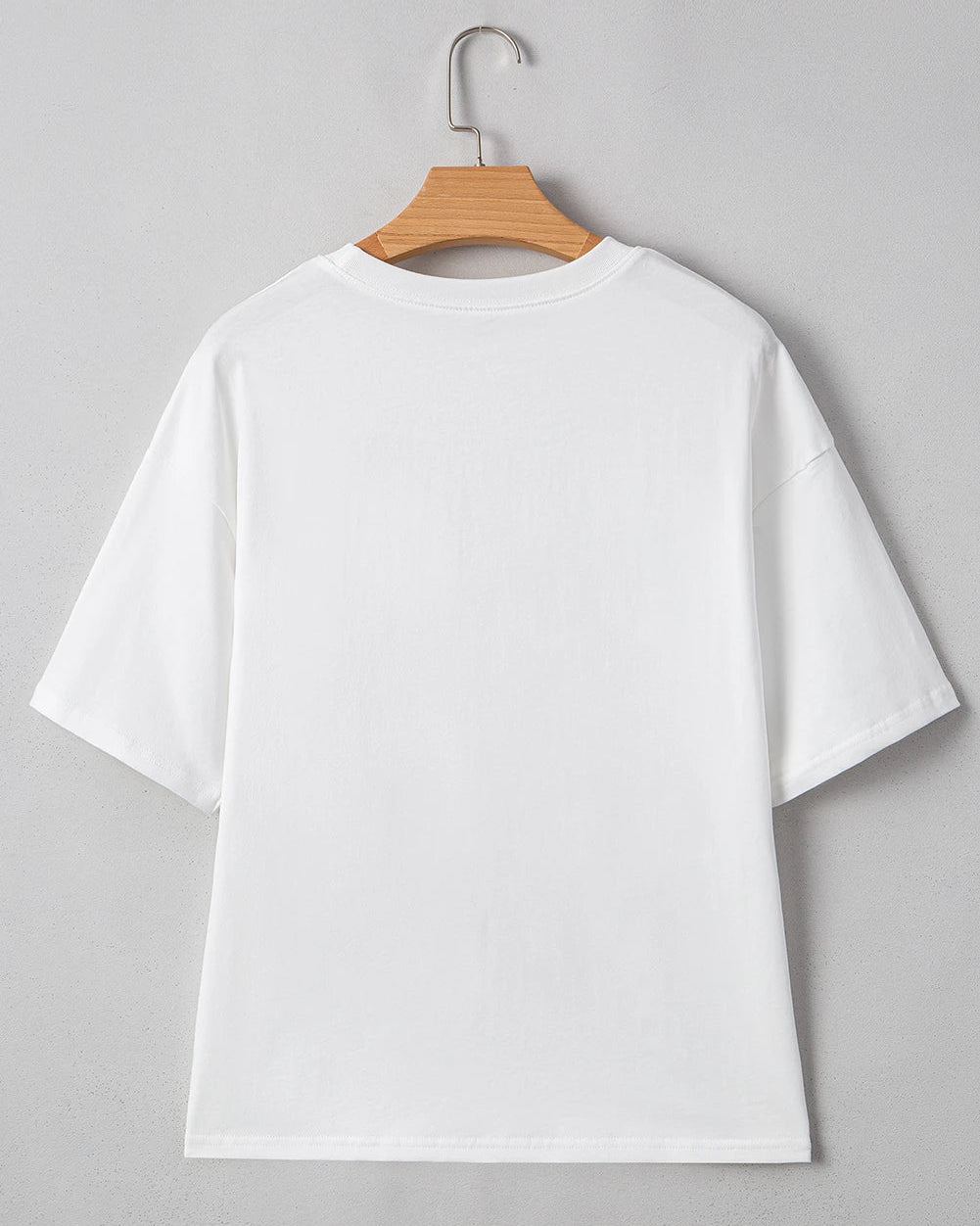 White t-shirt on a wooden hanger against a gray background