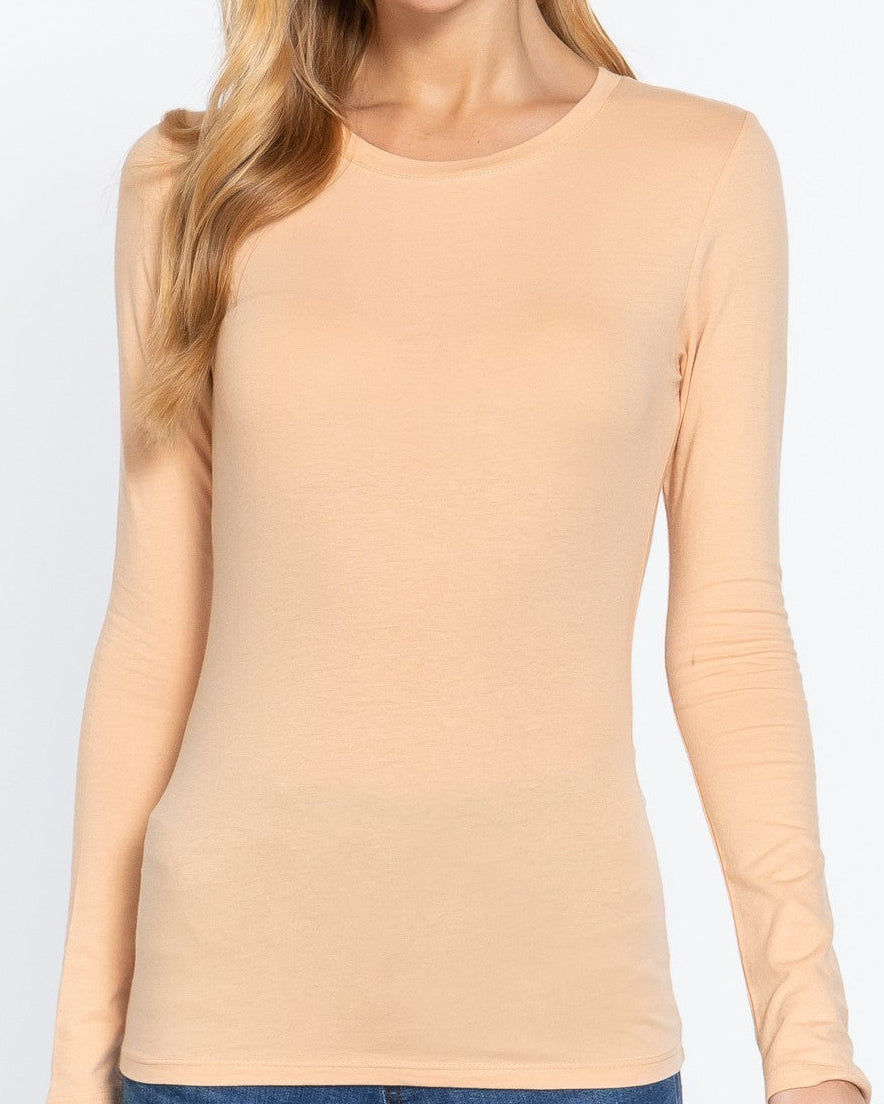 Woman wearing a beige long-sleeve top against a white background