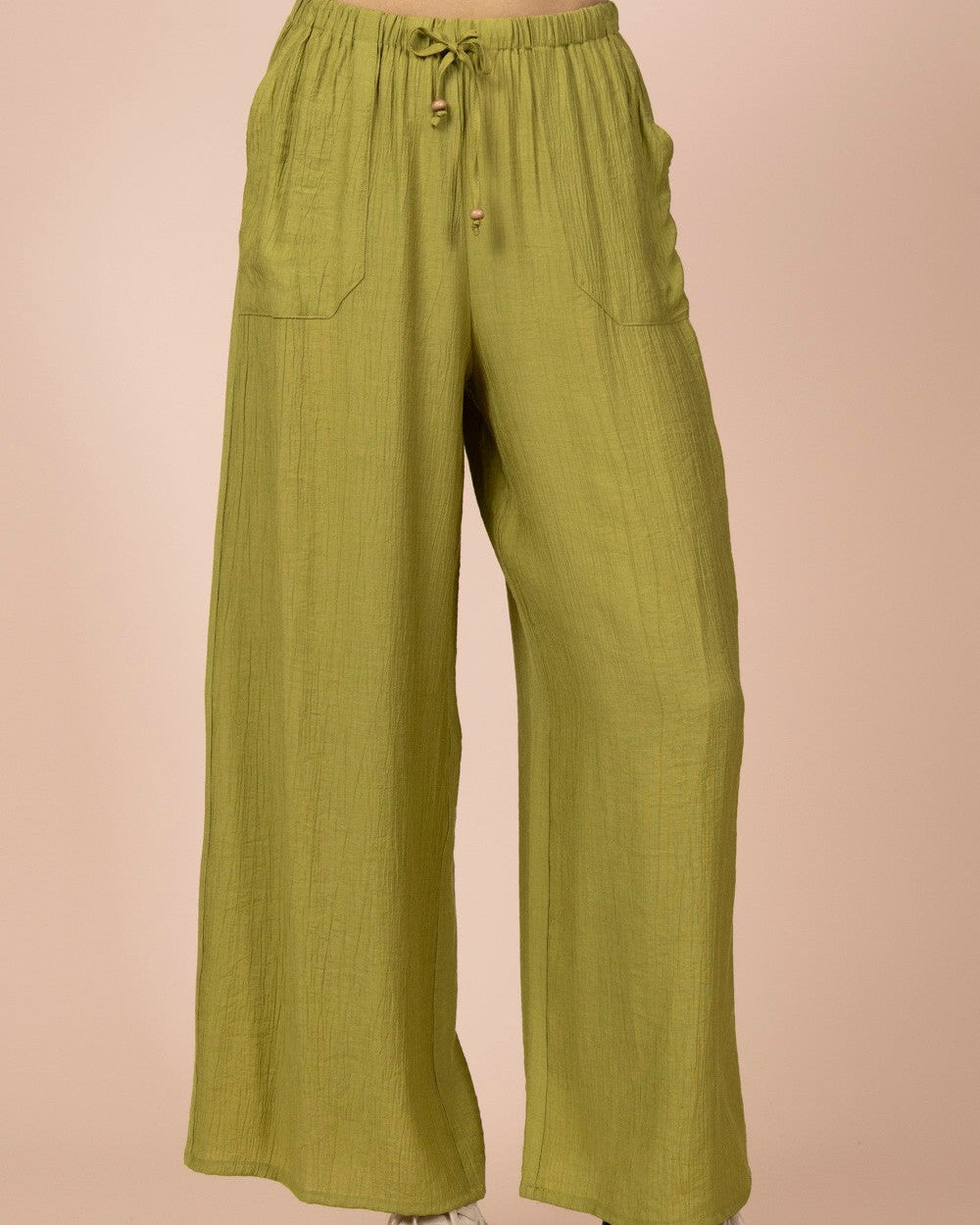 Green wide-leg pants worn by a person on a beige background