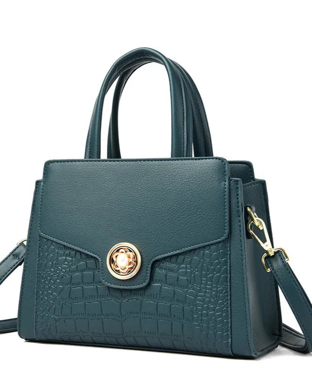 Teal handbag with gold clasp on a white background