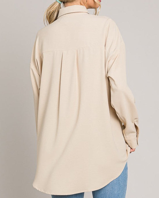 Woman wearing a beige coat and blue jeans on a plain background