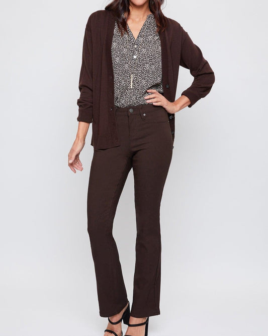 Woman wearing a brown cardigan, patterned blouse, and dark pants on a white background