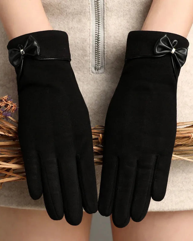 Black gloves with bow details on a neutral background