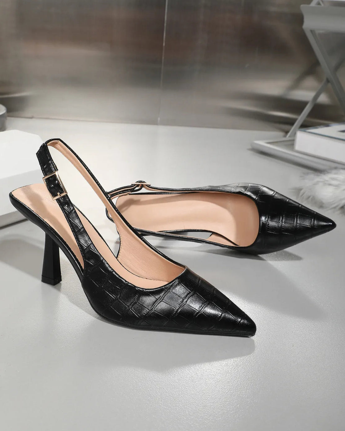 Black high-heeled shoes on a reflective surface