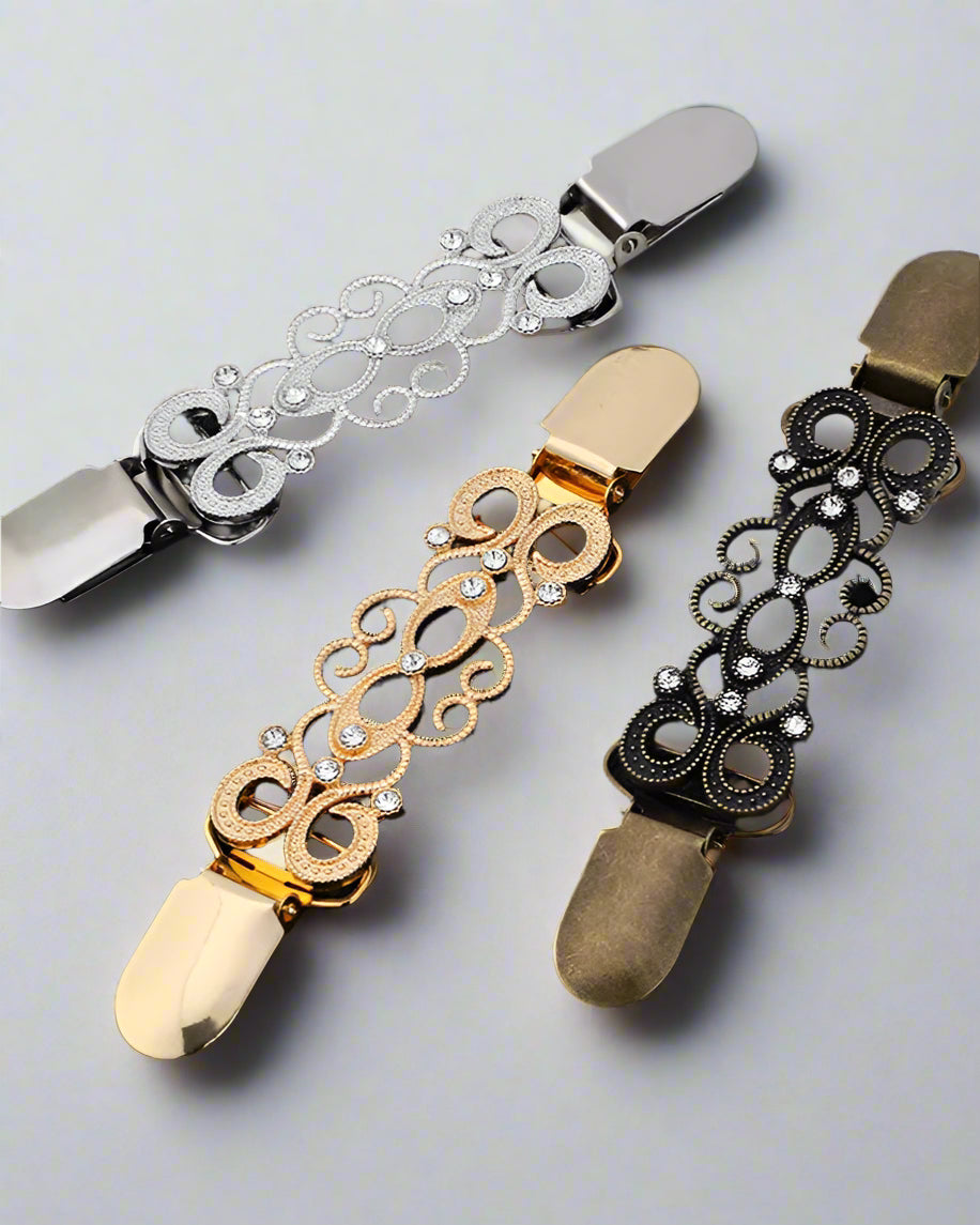 Trio of gold, silver, and bronze vintage scarf clips on black background