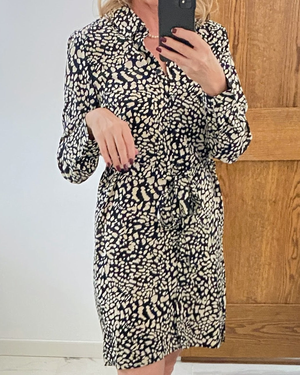 Person wearing a leopard print dress taking a mirror selfie.