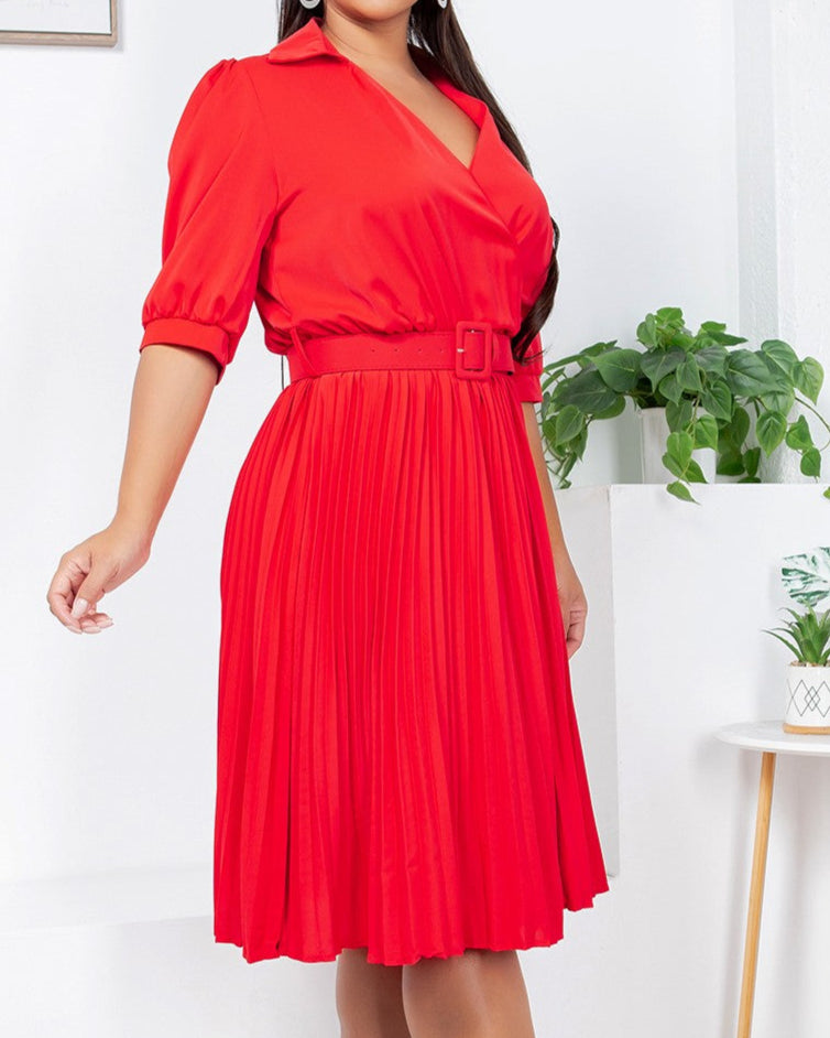 Woman wearing a red dress in an indoor setting with plants and a white wall.