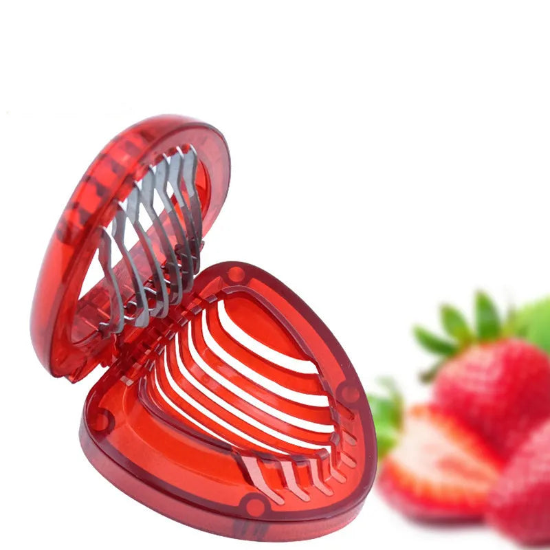 Red strawberry slicer with a clear heart design, surrounded by strawberries on a white background.