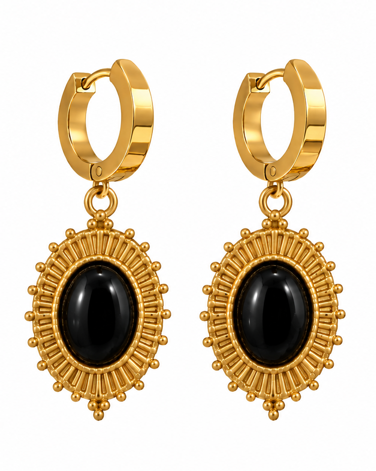 Gold huggie hoop earrings with oval black onyx centers, shown on a white background and worn on a model's ear.