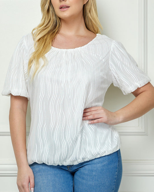 Woman wearing a white blouse and blue jeans against a white wall