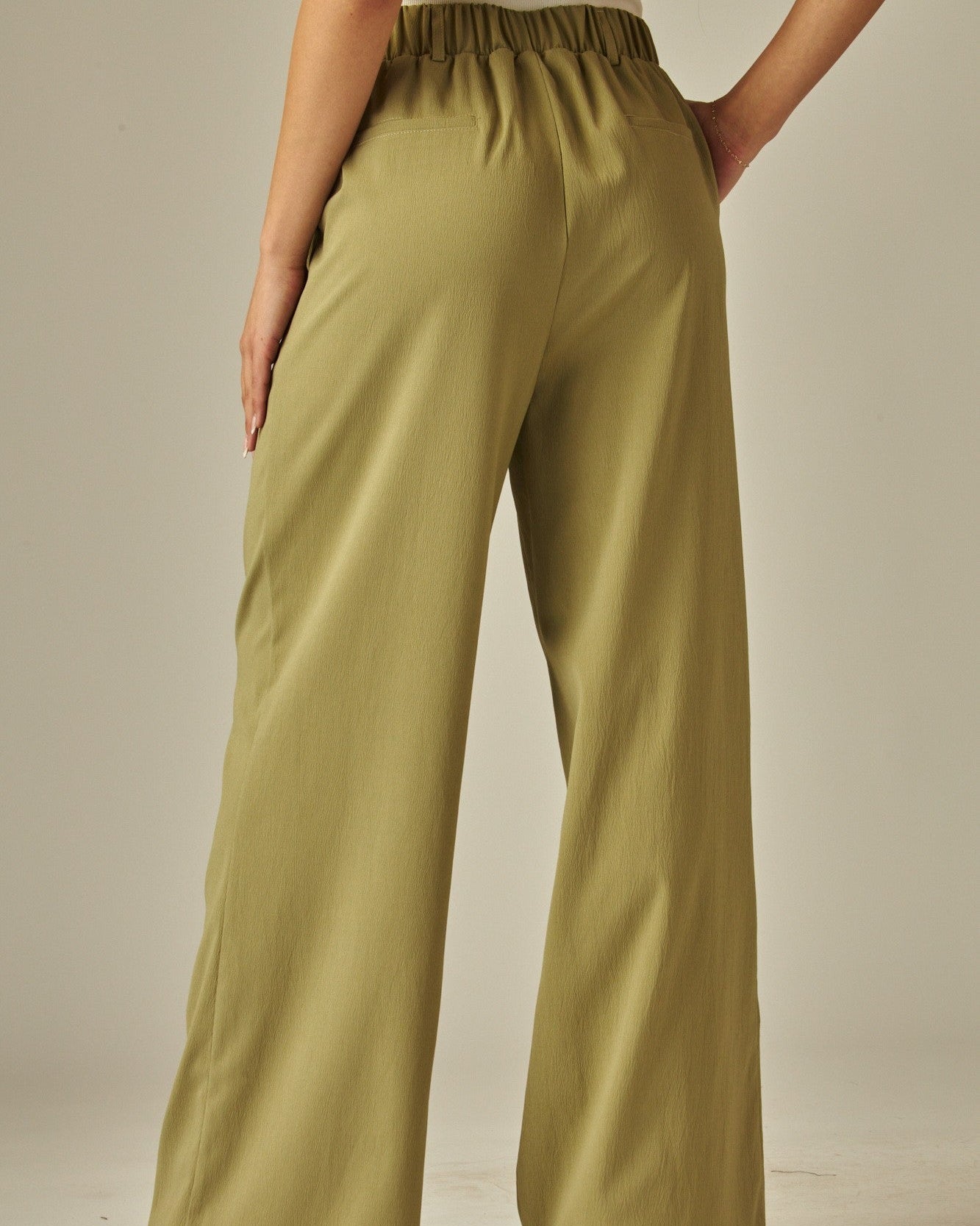 Person wearing olive green wide-leg pants on a neutral background
