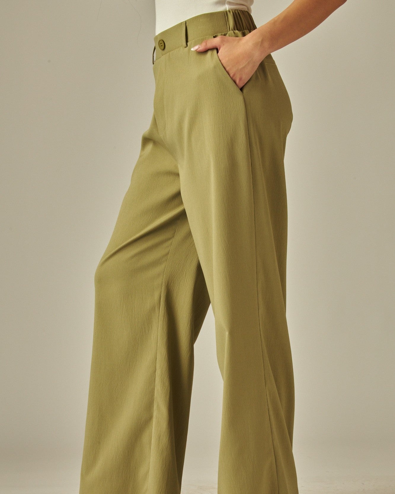 Person wearing olive green pants on a plain background