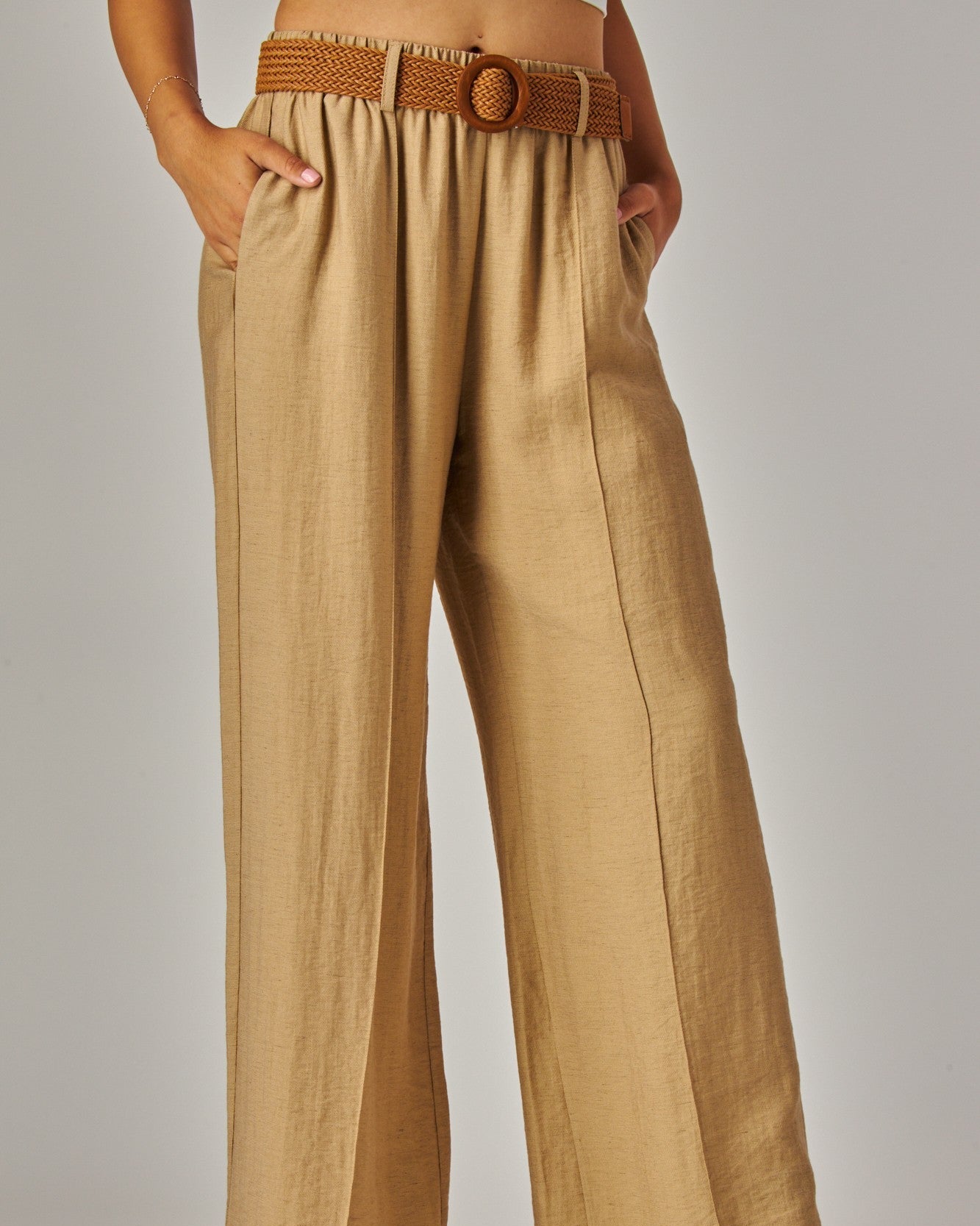 Beige wide-leg pants with a brown belt on a plain background
