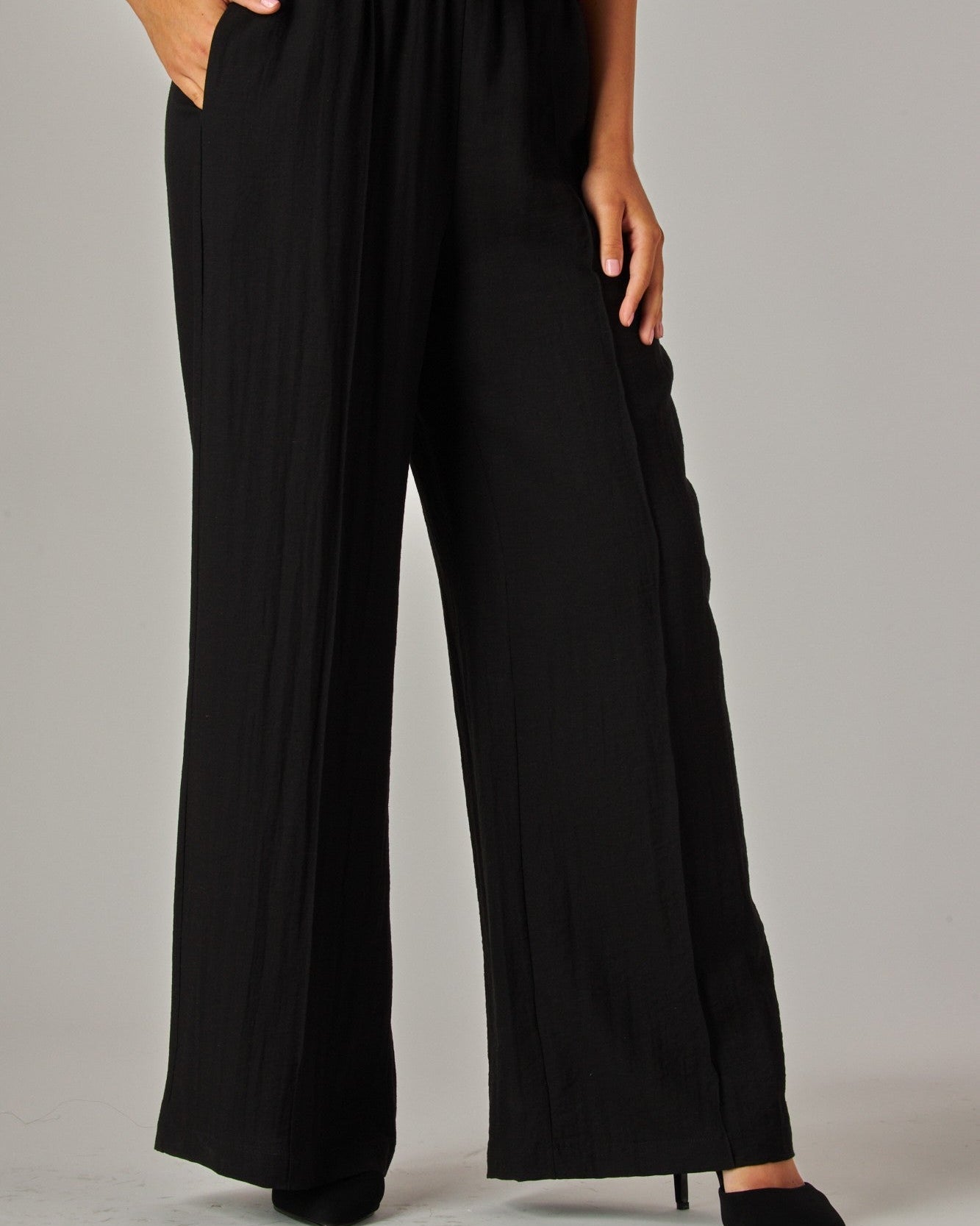 Black wide-leg pants with a brown belt on a plain background
