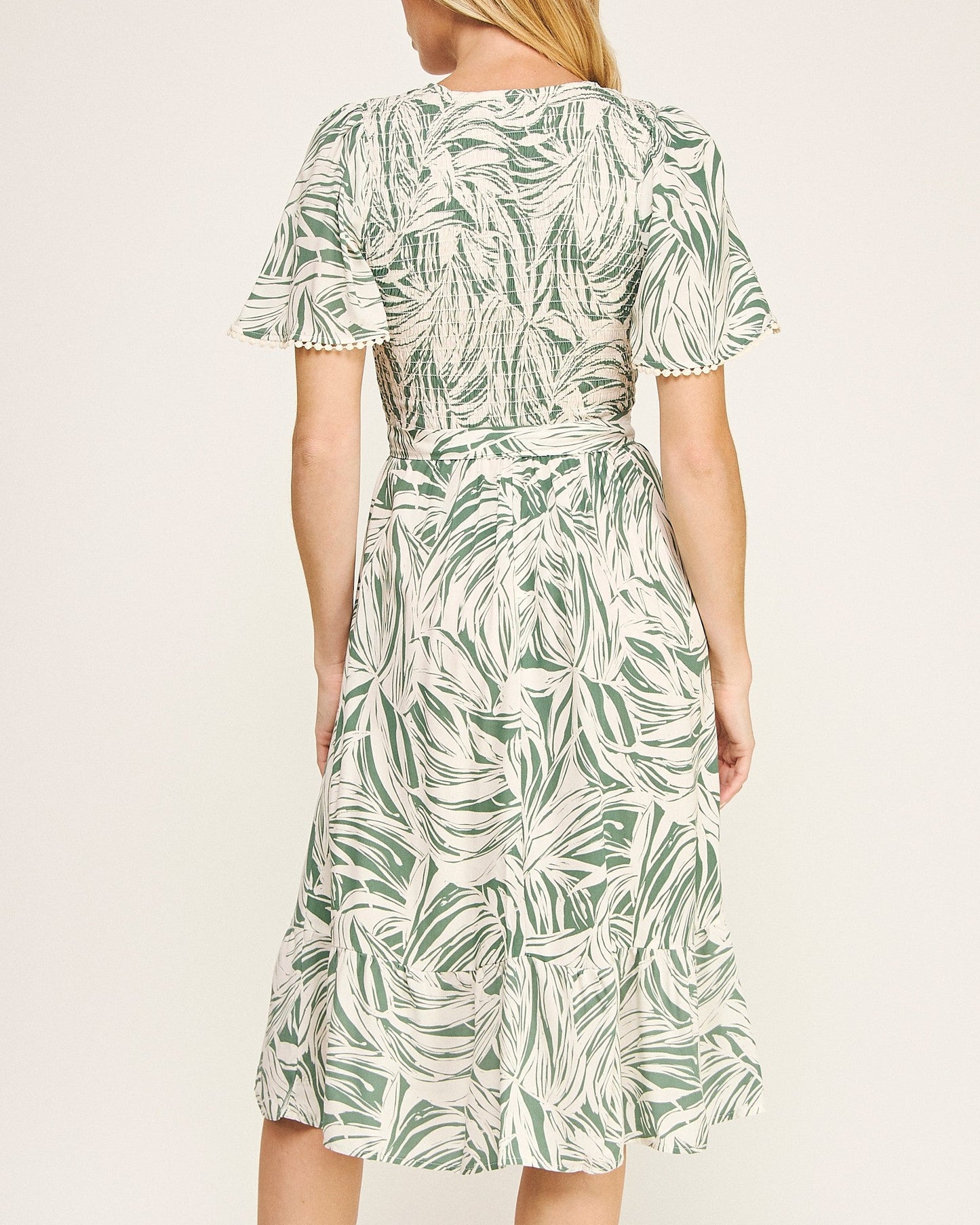Woman wearing a green leaf pattern dress on a white background