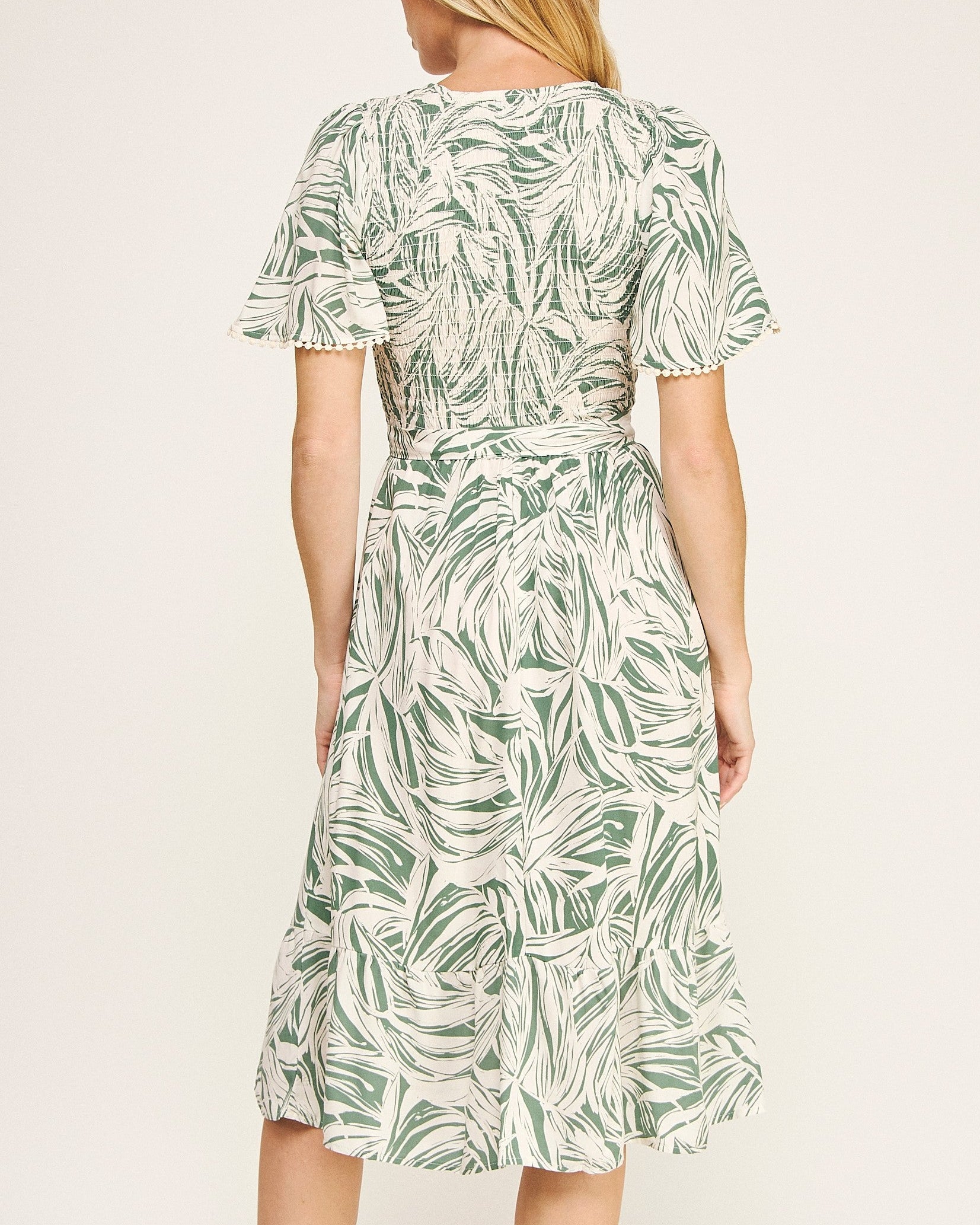 Woman wearing a green leaf pattern dress on a white background