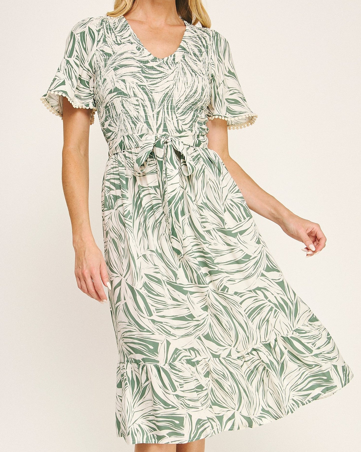 Woman wearing a green leaf-patterned dress on a white background