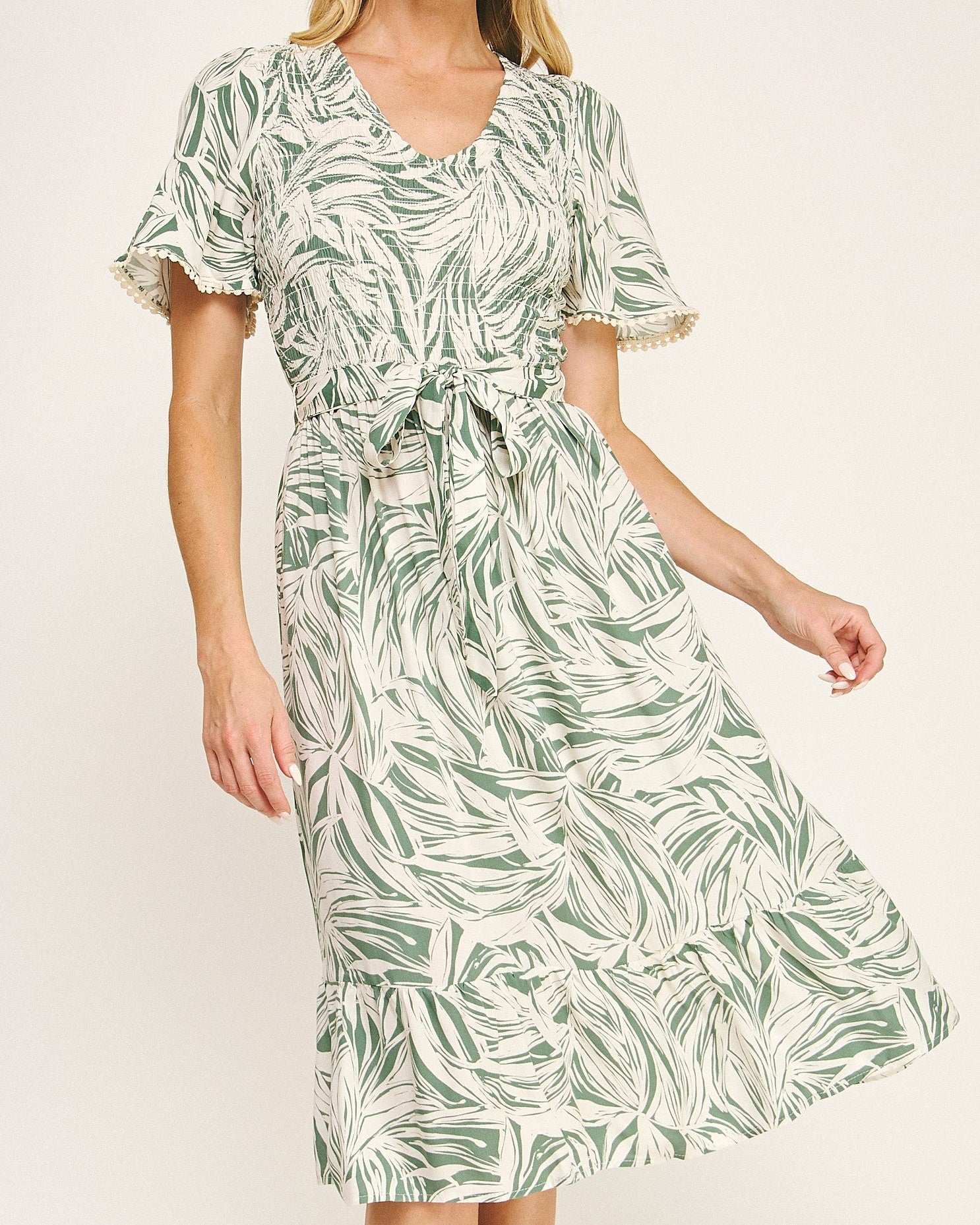 Woman wearing a green leaf-patterned dress on a white background