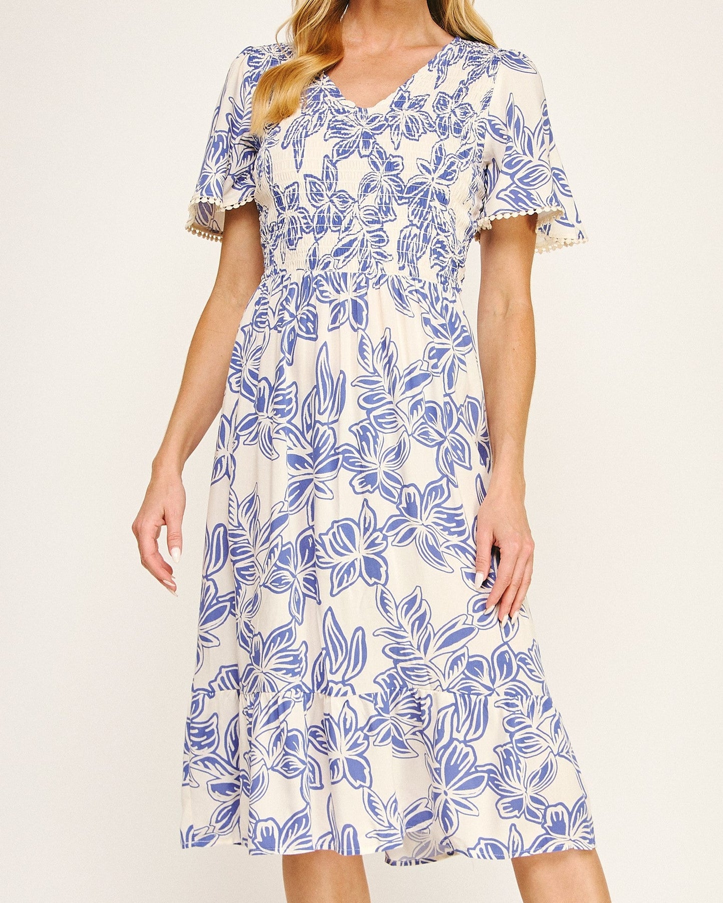 Woman wearing a blue and white floral dress on a plain background