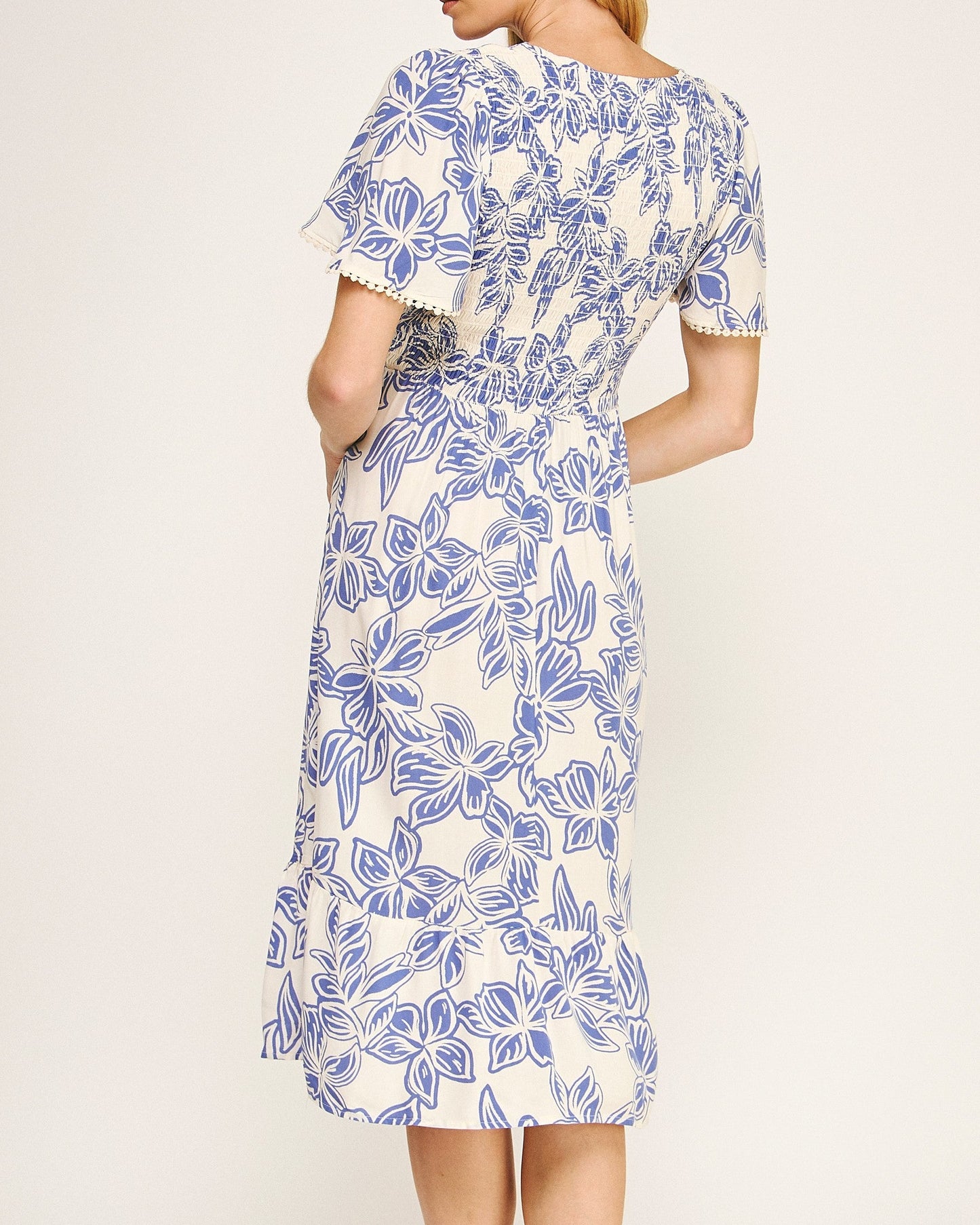 Woman wearing a blue and white floral dress on a plain background