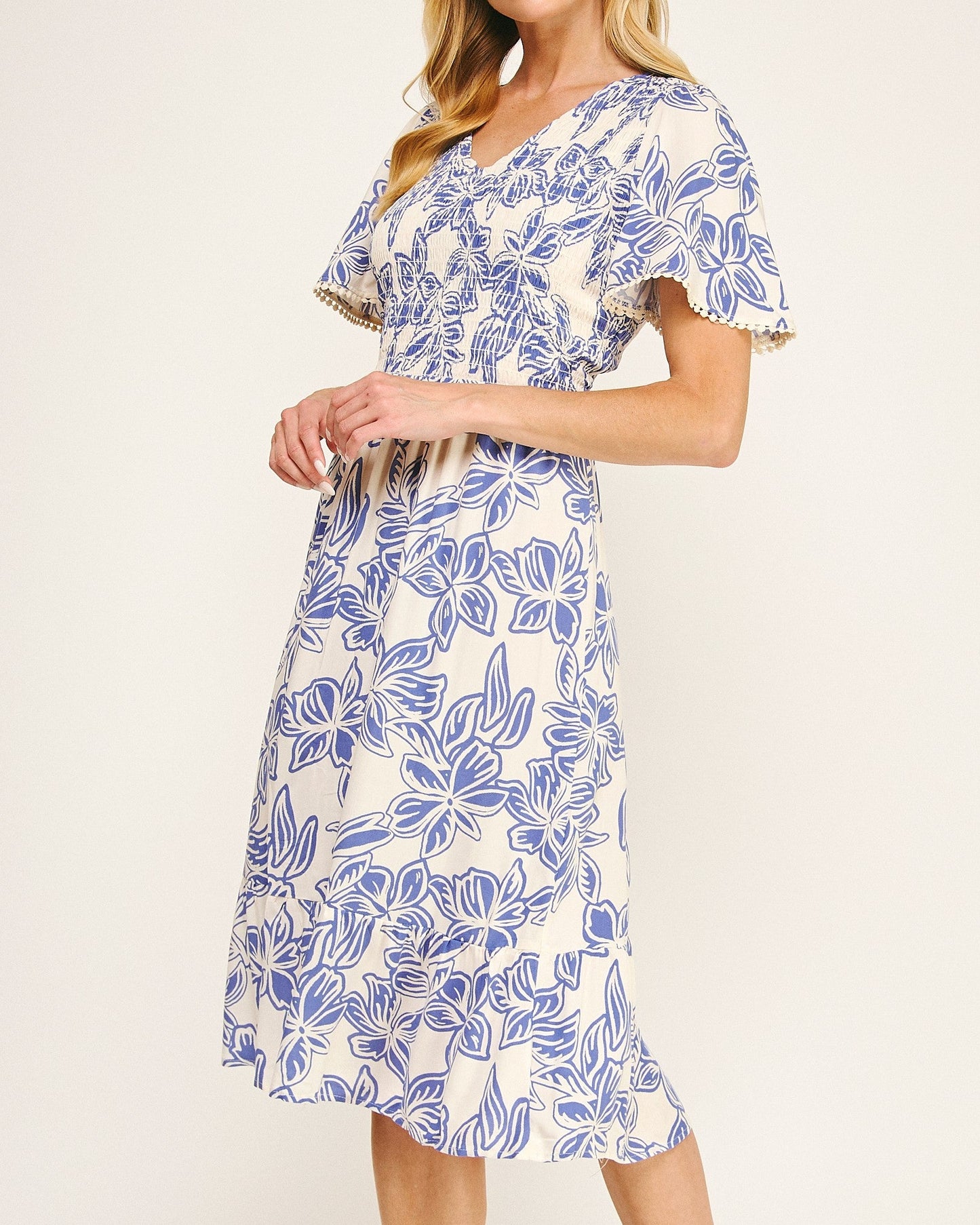 Woman wearing a blue and white floral dress on a plain background