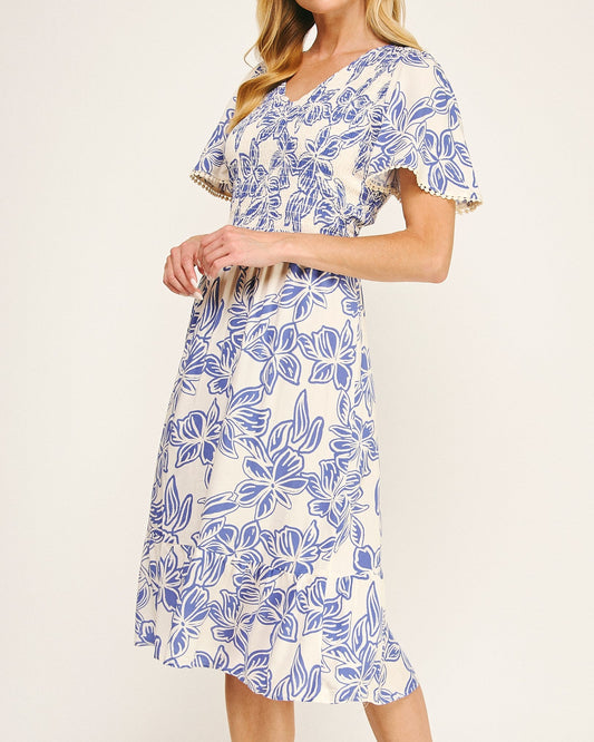 Woman wearing a blue and white floral dress on a plain background