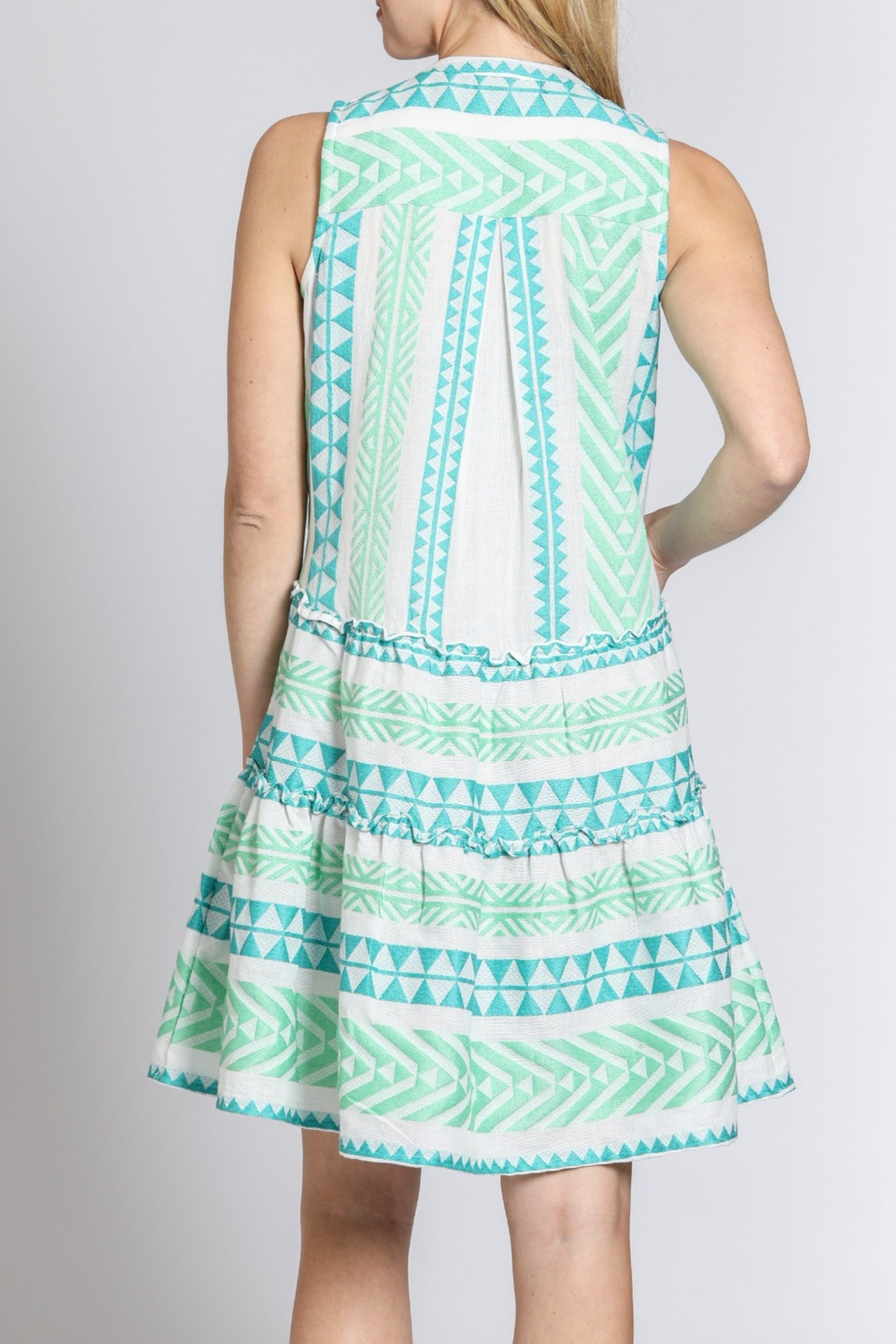 Woman wearing a sleeveless dress with a geometric pattern on a plain background