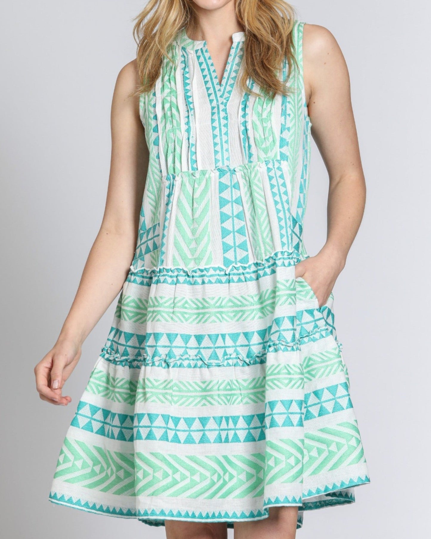 Woman wearing a green and white patterned dress on a plain background