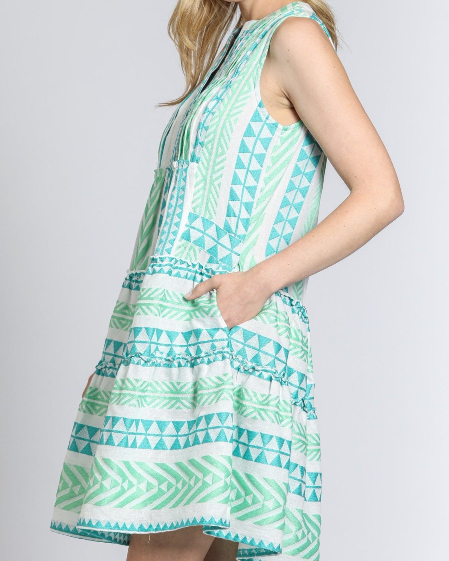 Woman wearing a green and white patterned dress on a plain background
