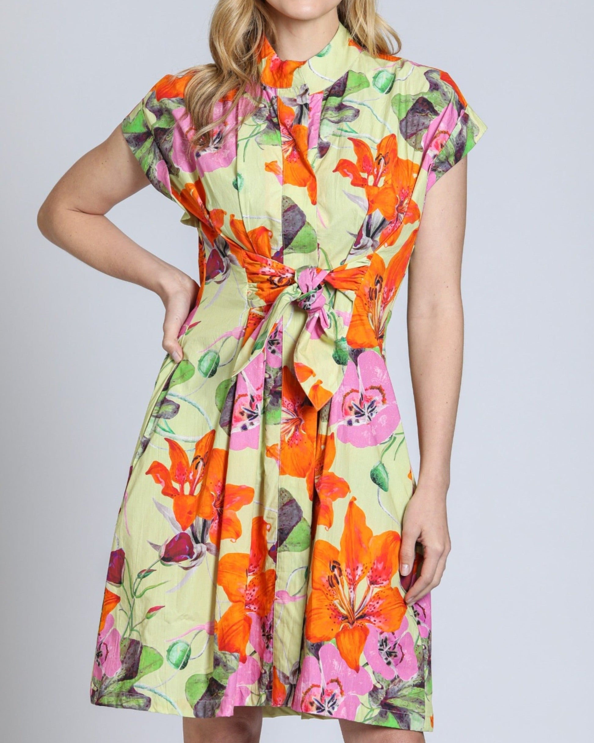 Woman wearing a colorful floral dress against a plain background
