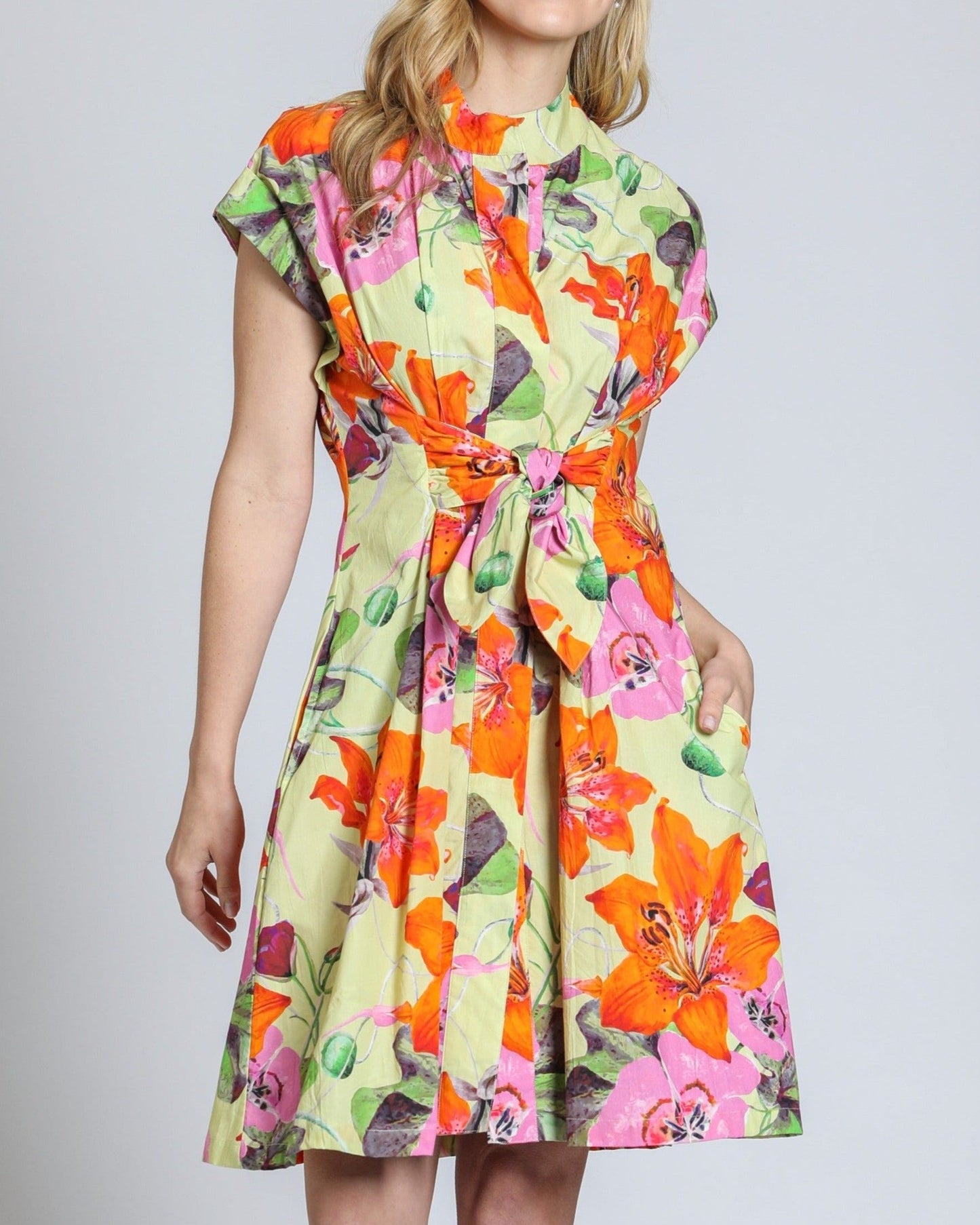 Woman wearing a colorful floral dress on a plain background