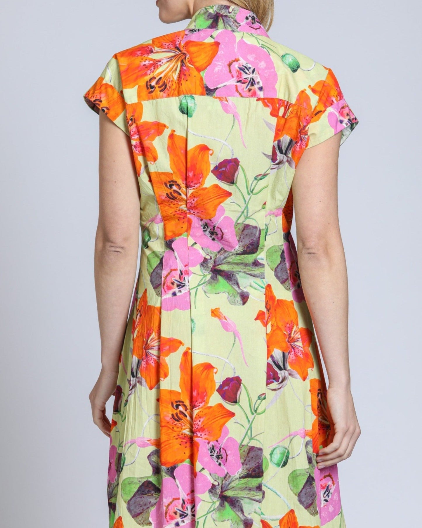 Woman wearing a colorful floral dress against a plain background
