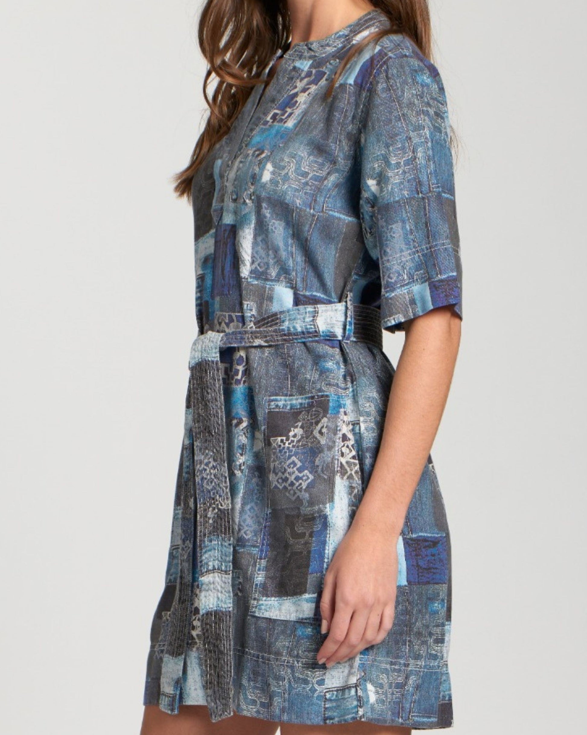 Woman wearing a blue patterned dress on a plain background