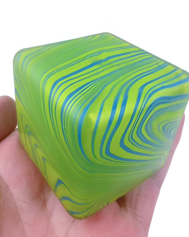 Green and blue marbled cube held in a hand against a white background