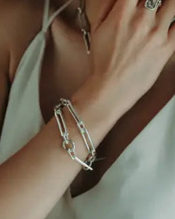 Woman wearing jewelry including earrings, a ring, and a bracelet.