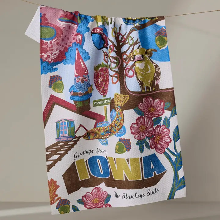 Colorful towel with Iowa-themed design featuring gnomes, trees, and flowers on a neutral background.
