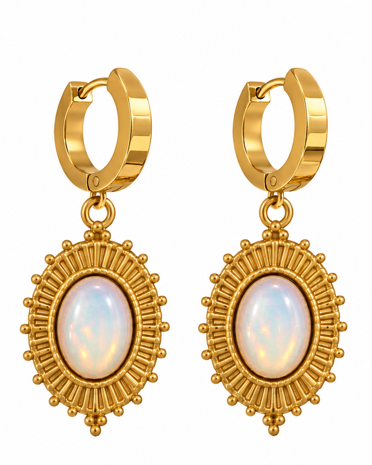 Gold huggie hoop earrings with oval iridescent opal-like centers, shown on a white background and worn on a model's ear.