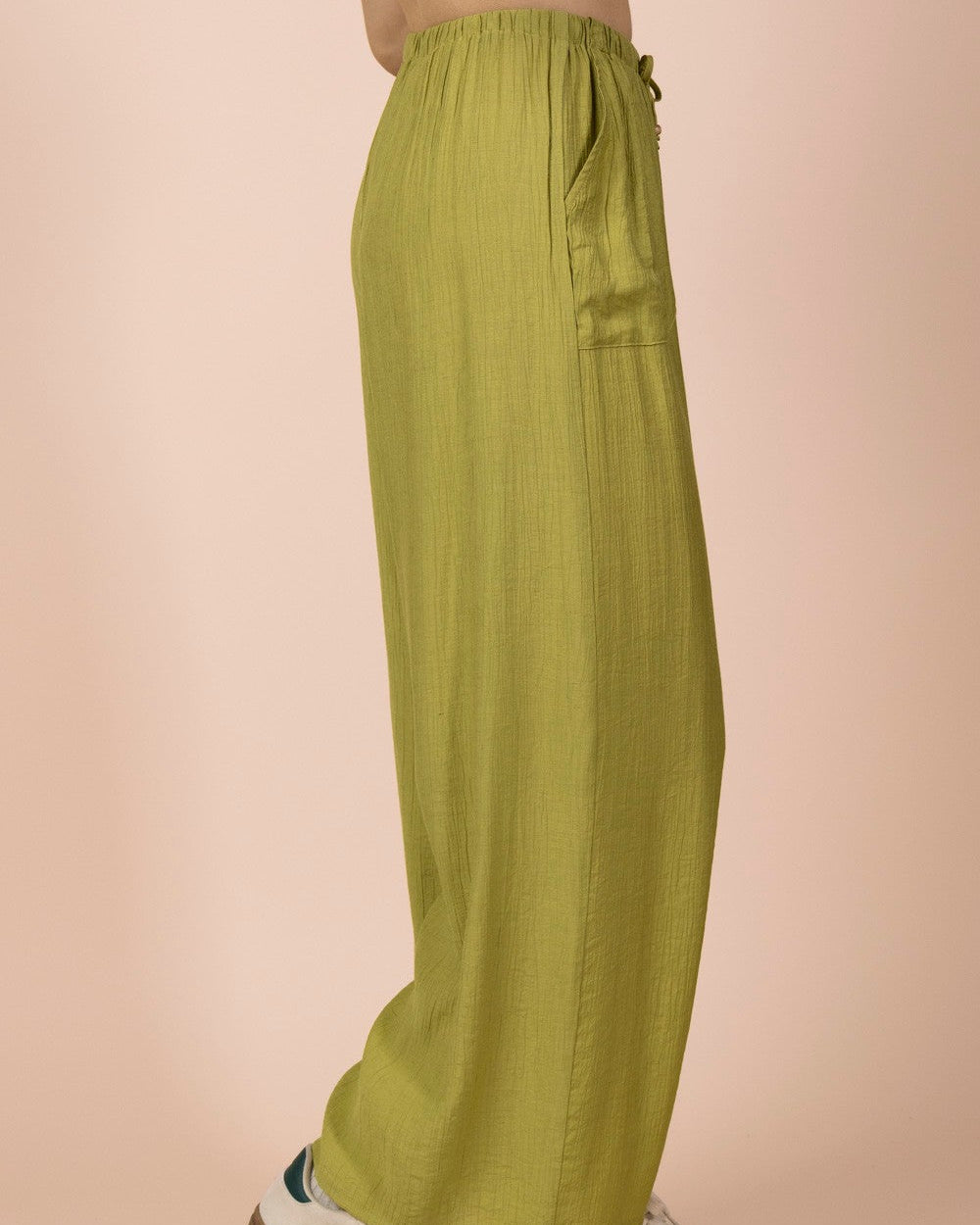 Person wearing green wide-leg pants with a beige background