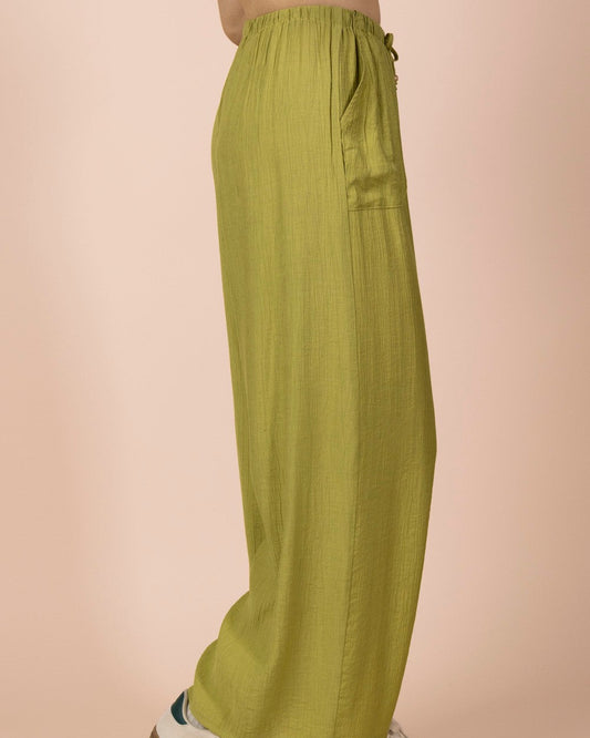 Person wearing green wide-leg pants with a beige background