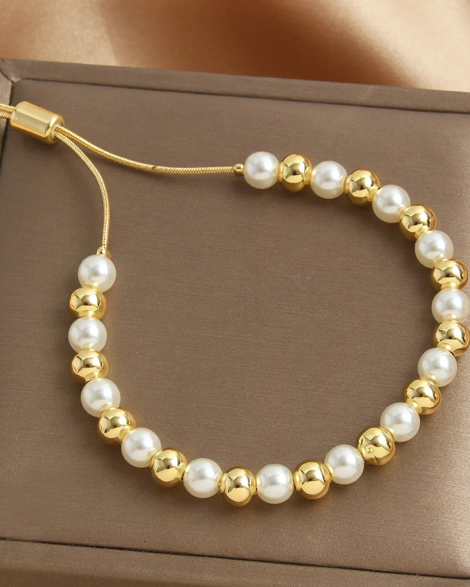 Bracelet with gold and white beads on a brown box