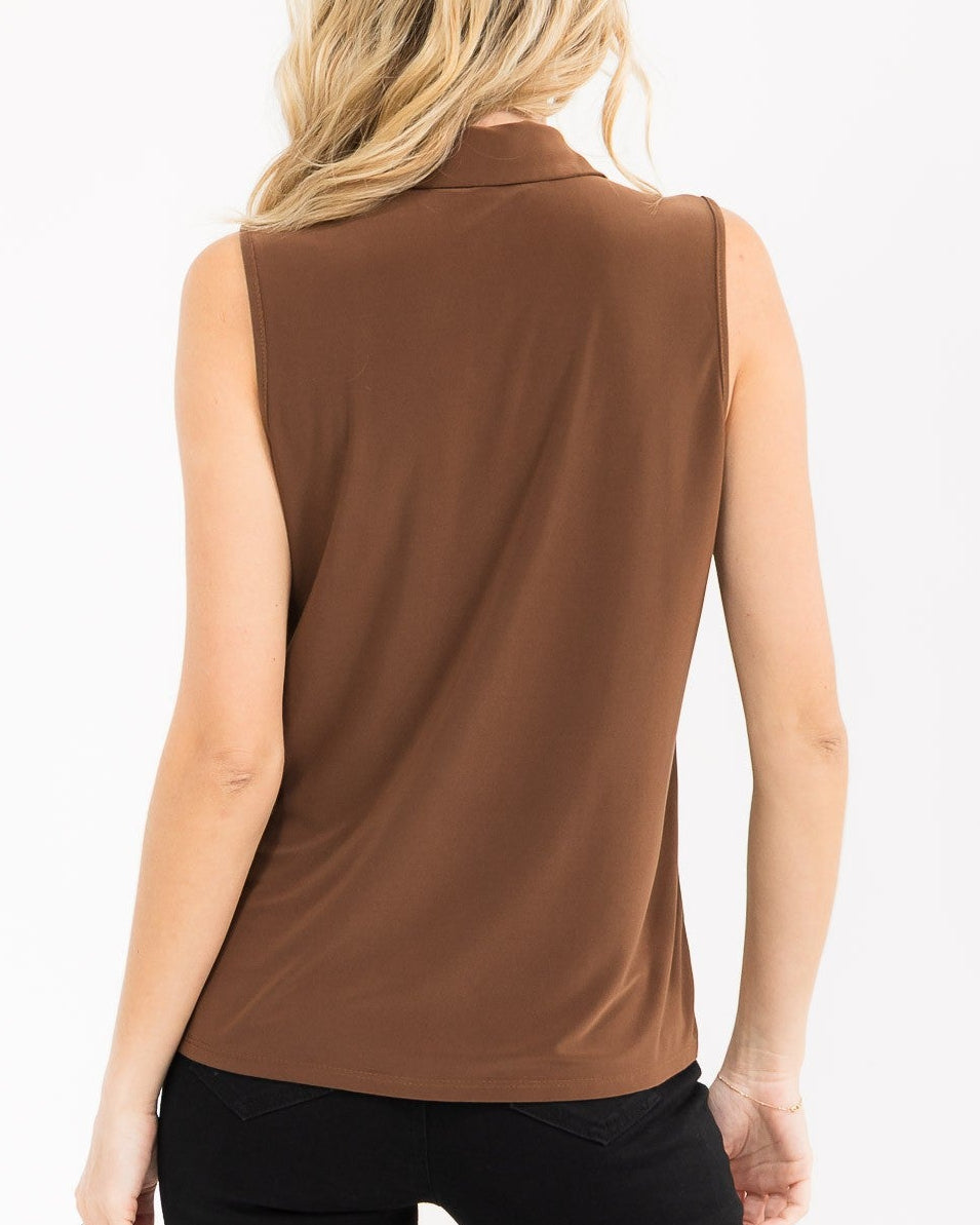 A woman shown from the back wearing a sleeveless brown collared top and black pants against a plain white background.