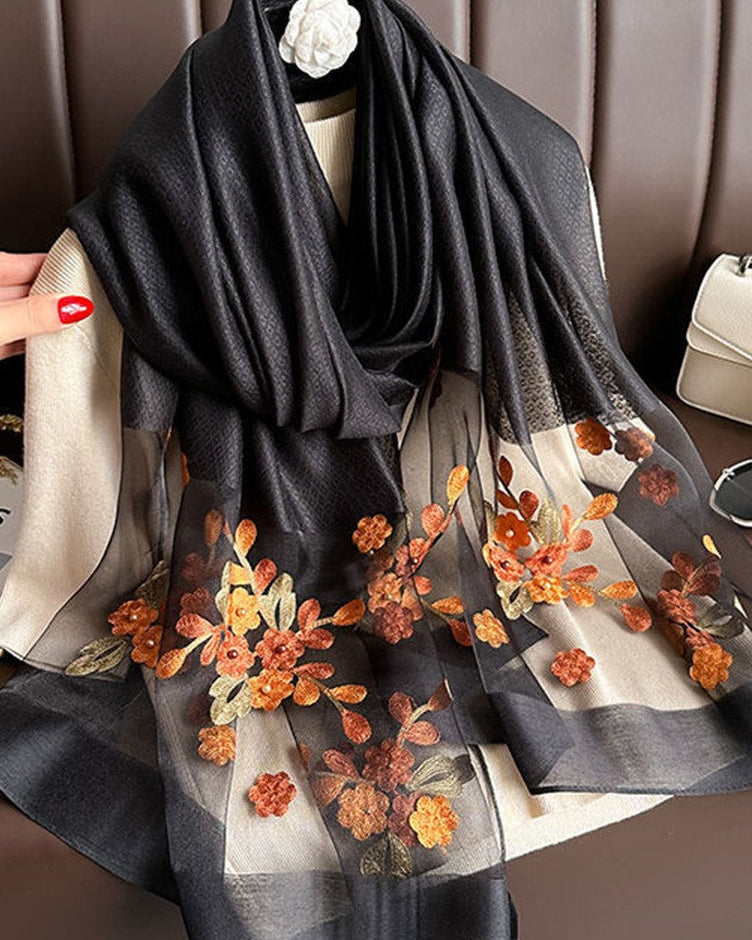 Black scarf with floral embroidery draped over a mannequin against a brown background
