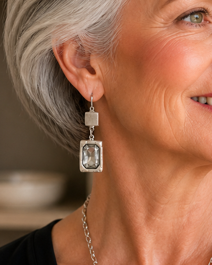 Woman with gray hair wearing a black top and necklace indoors