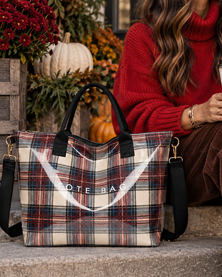 A woman sits on outdoor stone steps wearing a red turtleneck sweater, brown corduroy pants, and dark brown heeled boots, holding a coffee cup next to a large plaid tote bag. The bag has black handles and straps with gold-tone hardware and a white printed logo reading 'NOTE BAG'.