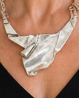 Woman wearing a black top and silver necklace indoors