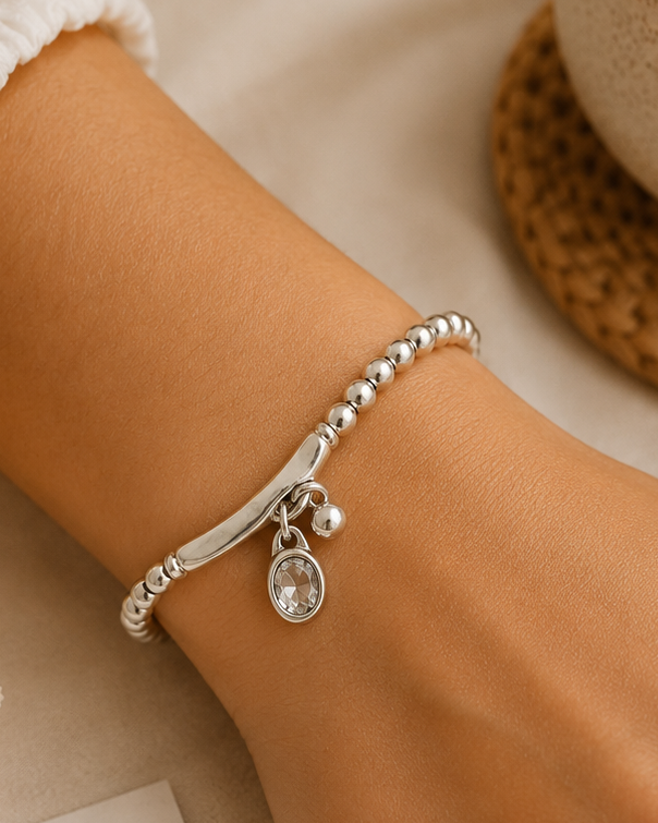 Silver bracelet on a wrist with a cup and card in the background