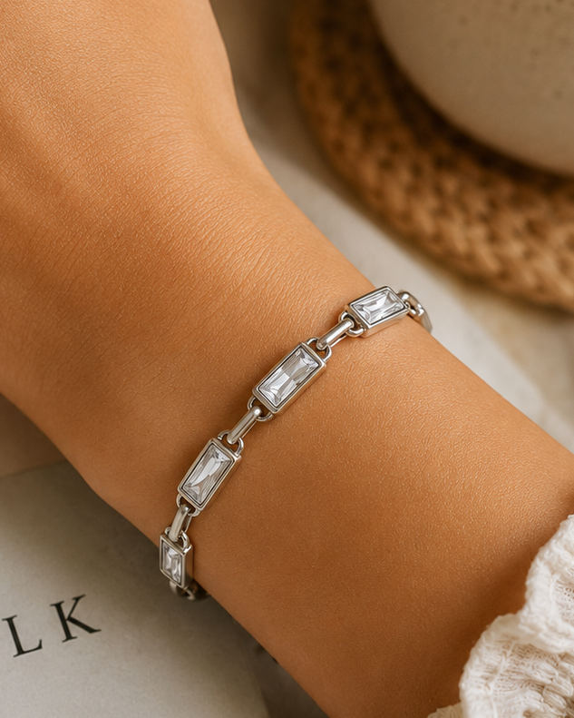 Silver bracelet on a wrist with a cup and book in the background